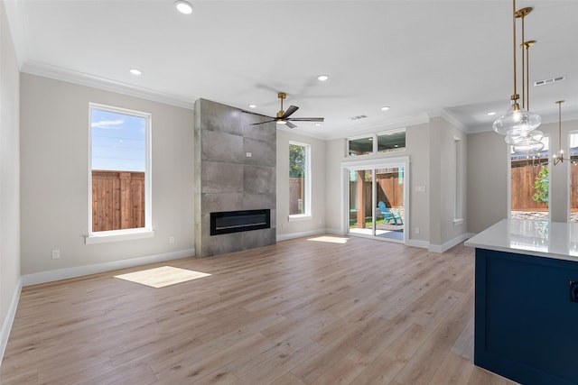 unfurnished living room with light wood-style flooring, recessed lighting, visible vents, a tiled fireplace, and crown molding