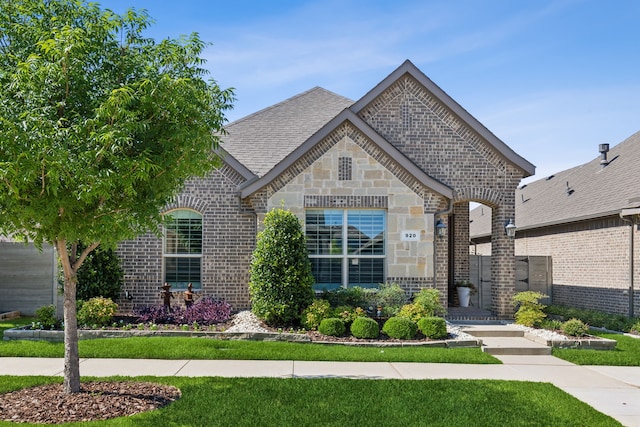 view of front of house featuring stone siding, roof with shingles, and brick siding