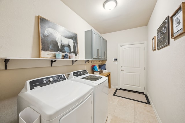 laundry area featuring cabinet space, washer and clothes dryer, baseboards, and light tile patterned flooring