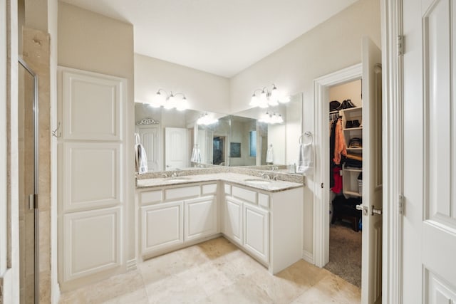 bathroom with a stall shower, a sink, a spacious closet, and double vanity