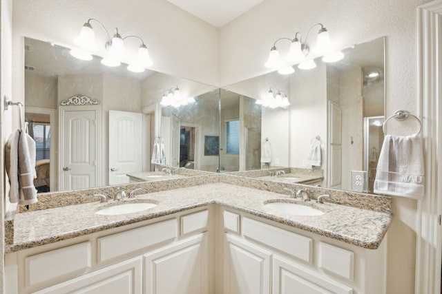 full bath featuring double vanity, a stall shower, a sink, and an inviting chandelier