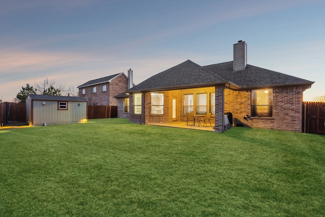 back of property featuring an outbuilding, brick siding, a yard, and a fenced backyard