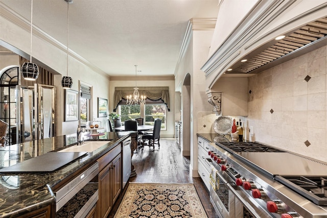 kitchen with dark wood-style flooring, a notable chandelier, decorative backsplash, appliances with stainless steel finishes, and premium range hood