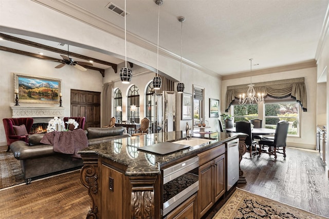 kitchen featuring a warm lit fireplace, dark wood-style flooring, a sink, visible vents, and stainless steel microwave