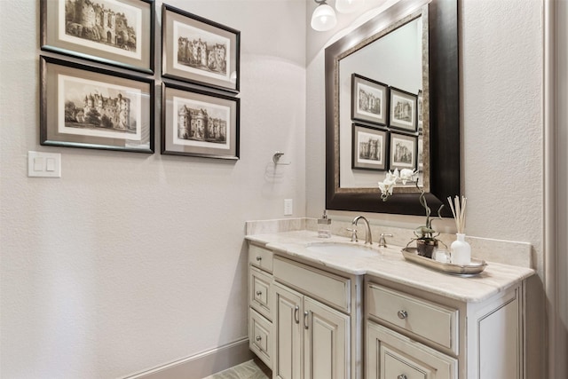 bathroom with a textured wall, baseboards, and vanity