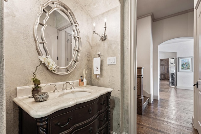 bathroom with crown molding, vanity, baseboards, and wood finished floors