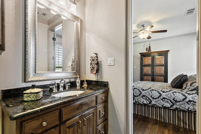 bathroom featuring visible vents, ceiling fan, wood finished floors, crown molding, and vanity