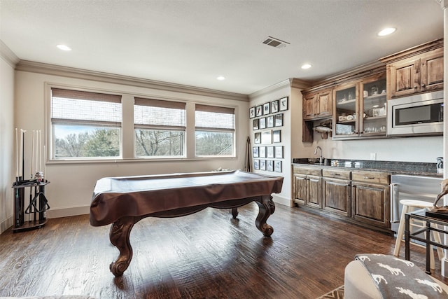 recreation room featuring ornamental molding, dark wood-type flooring, visible vents, and baseboards