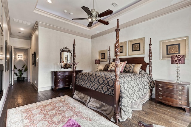 bedroom featuring wood finished floors, a raised ceiling, visible vents, and crown molding