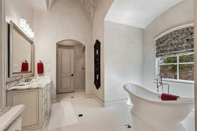 bathroom with a soaking tub, baseboards, and vanity