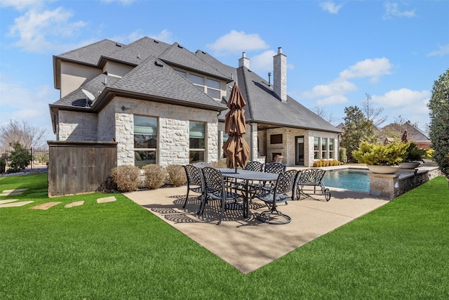 back of property featuring a yard, a shingled roof, a chimney, and a patio