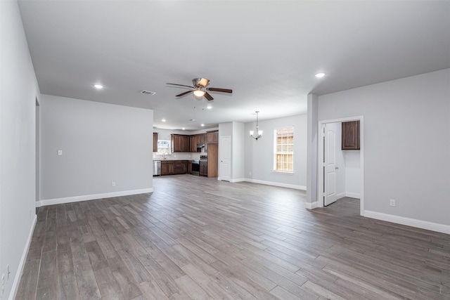 unfurnished living room with baseboards, visible vents, wood finished floors, ceiling fan with notable chandelier, and recessed lighting