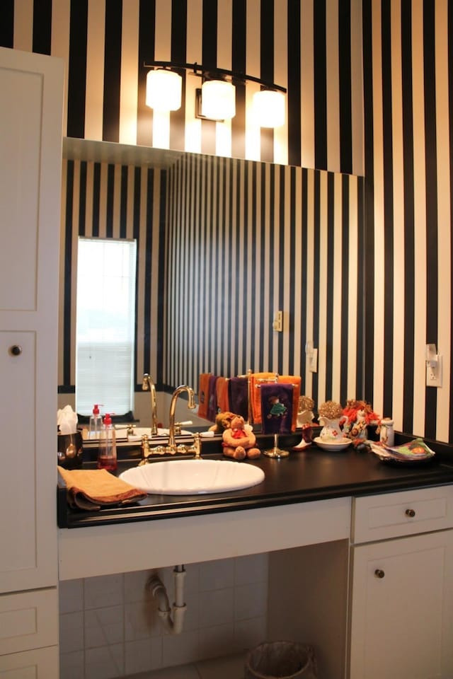 bathroom featuring a sink and wallpapered walls