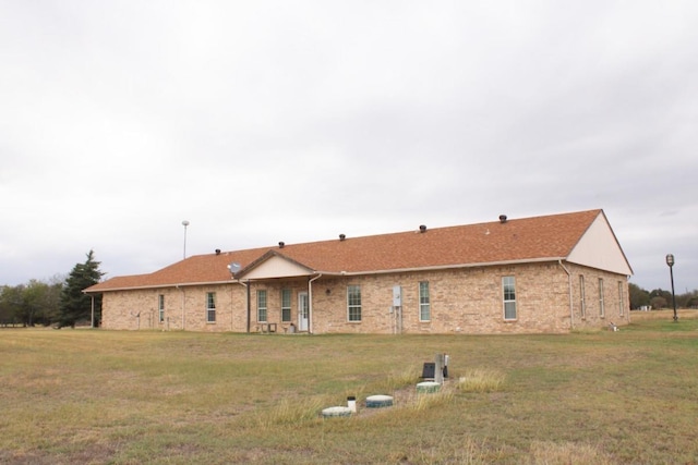 rear view of property featuring a lawn and brick siding