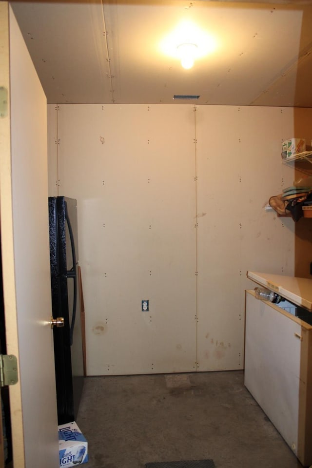 kitchen with concrete flooring and freestanding refrigerator