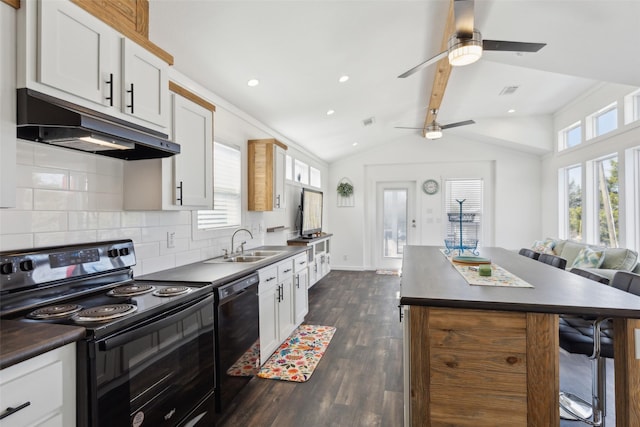 kitchen featuring under cabinet range hood, a breakfast bar, a sink, black appliances, and dark countertops