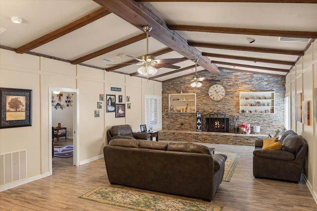 living room with visible vents, wood finished floors, vaulted ceiling with beams, a fireplace, and a decorative wall