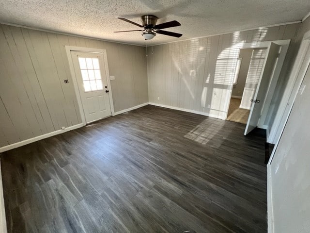 interior space with ceiling fan, baseboards, dark wood finished floors, and a textured ceiling