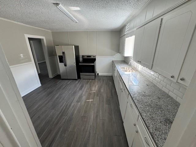 kitchen featuring stainless steel appliances, dark wood-style flooring, a sink, white cabinetry, and light stone countertops