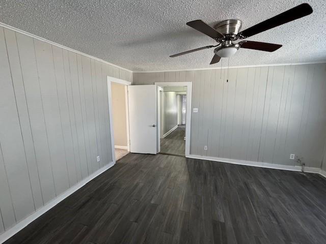 unfurnished bedroom with a textured ceiling, ornamental molding, dark wood-style flooring, and baseboards