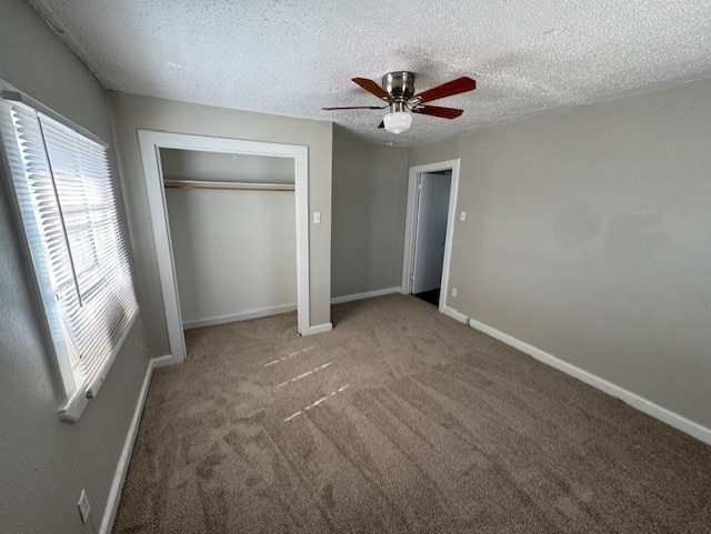 unfurnished bedroom featuring a textured ceiling, ceiling fan, carpet flooring, baseboards, and a closet