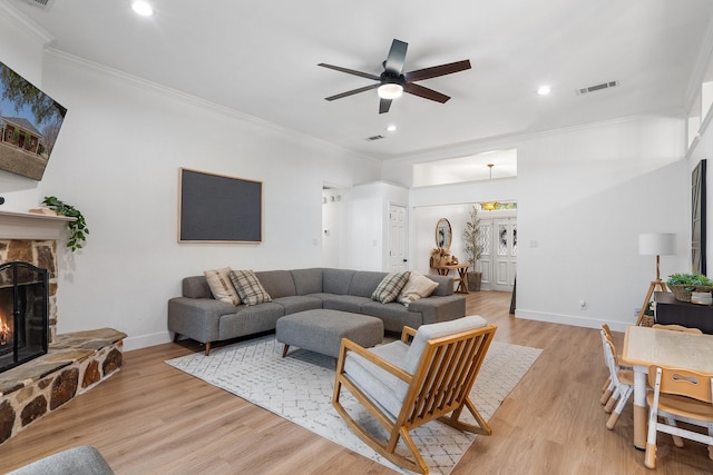 living room featuring light wood finished floors, baseboards, a fireplace, and ornamental molding