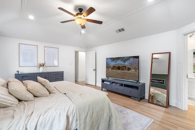 bedroom with connected bathroom, visible vents, baseboards, light wood-style floors, and a tray ceiling