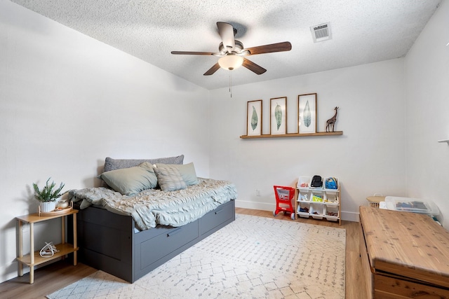 230 Holder Trl, Mckinney, TX 75071 - bedroom with wood finished floors, baseboards, a textured ceiling, and a ceiling fan