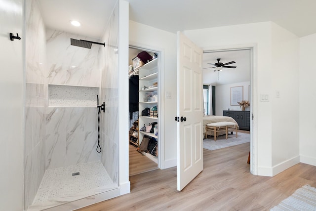 bathroom featuring baseboards, a marble finish shower, and wood finished floors