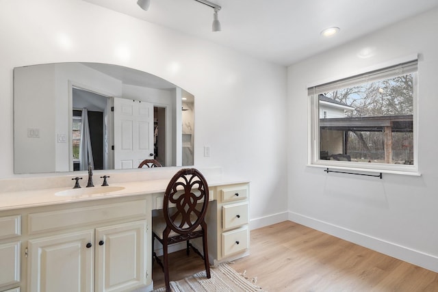 bathroom featuring track lighting, wood finished floors, vanity, and baseboards