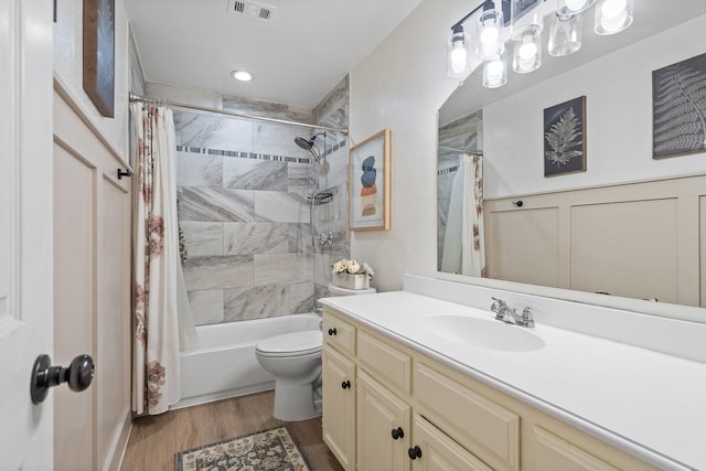 bathroom featuring toilet, wood finished floors, vanity, visible vents, and shower / bath combination with curtain