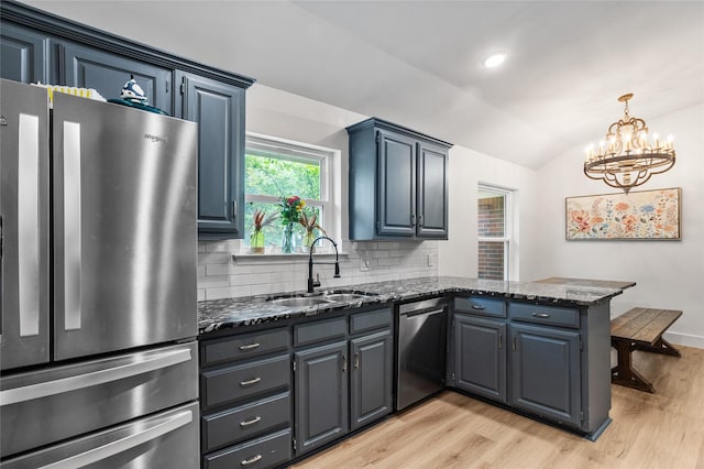 230 Holder Trl, Mckinney, TX 75071 - kitchen with stainless steel appliances, a peninsula, a sink, lofted ceiling, and light wood-type flooring