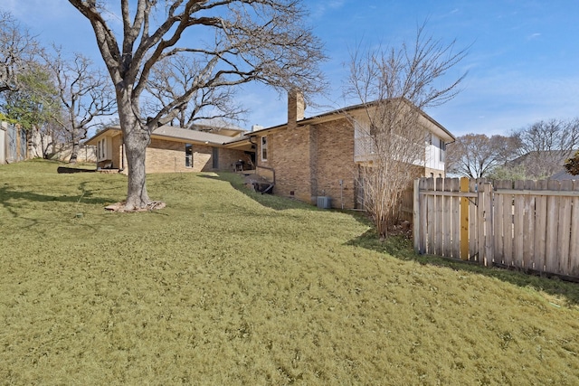 exterior space featuring brick siding, a lawn, a chimney, and fence