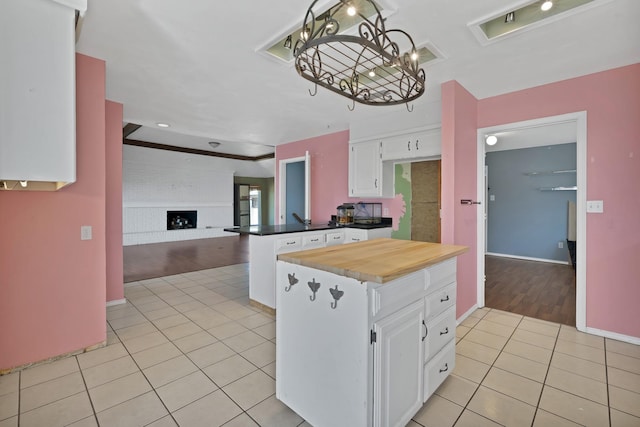 kitchen featuring light tile patterned floors, open floor plan, a fireplace, white cabinetry, and pendant lighting