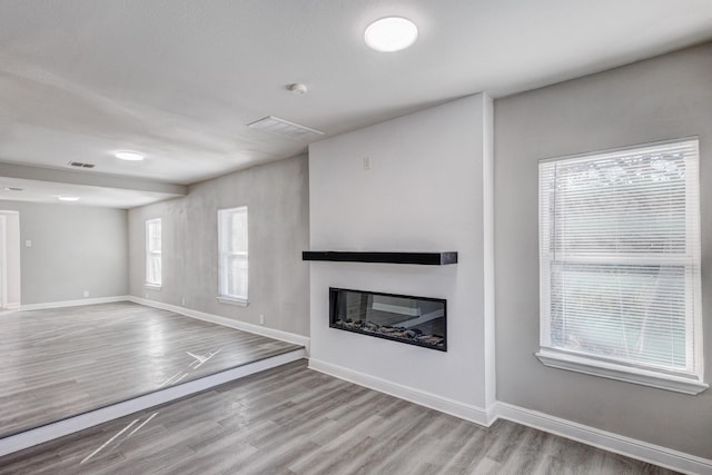 138 Whippoorwill Dr, Dallas, TX 75224 - unfurnished living room with a glass covered fireplace, wood finished floors, and baseboards