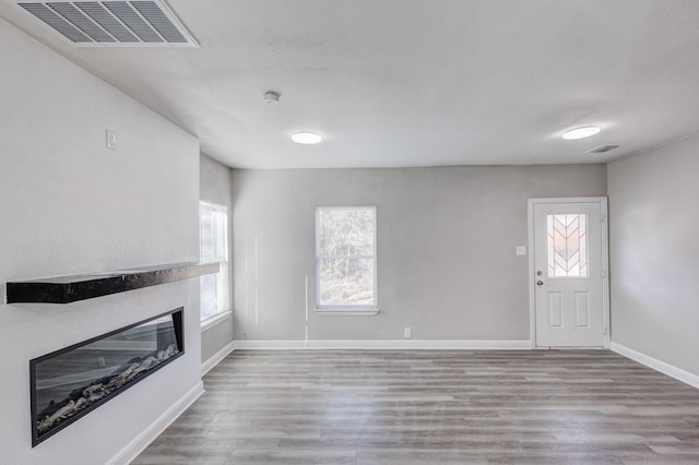 138 Whippoorwill Dr, Dallas, TX 75224 - unfurnished living room featuring a glass covered fireplace, wood finished floors, healthy amount of natural light, and baseboards