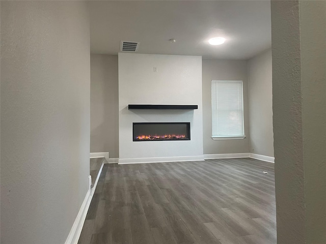 138 Whippoorwill Dr, Dallas, TX 75224 - unfurnished living room with dark wood finished floors, a glass covered fireplace, baseboards, and a textured wall