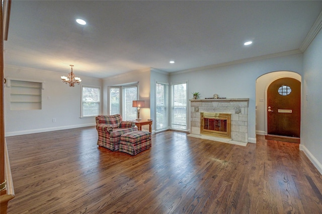 living room featuring crown molding, a tile fireplace, dark wood finished floors, and baseboards