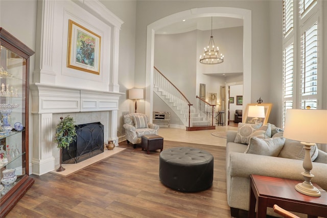 living room with stairs, dark wood finished floors, a notable chandelier, and a tile fireplace