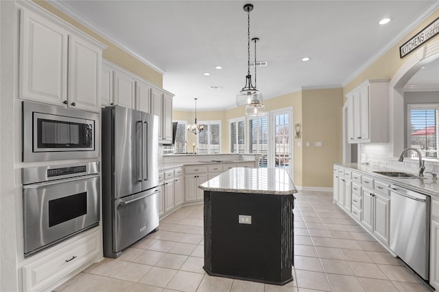 kitchen featuring light tile patterned floors, stainless steel appliances, a peninsula, and a sink