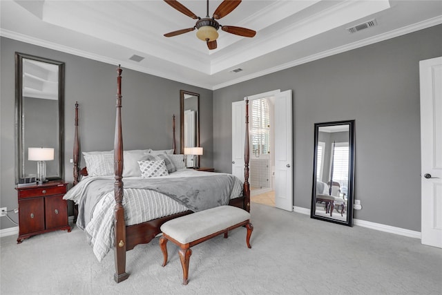 bedroom with a tray ceiling, visible vents, light carpet, and baseboards