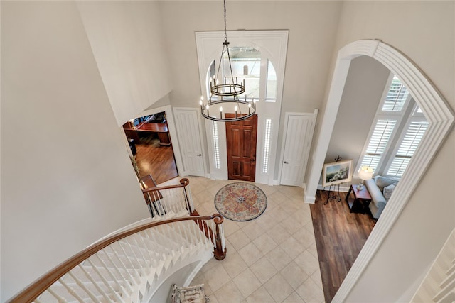 entrance foyer with a chandelier, tile patterned flooring, baseboards, and a high ceiling