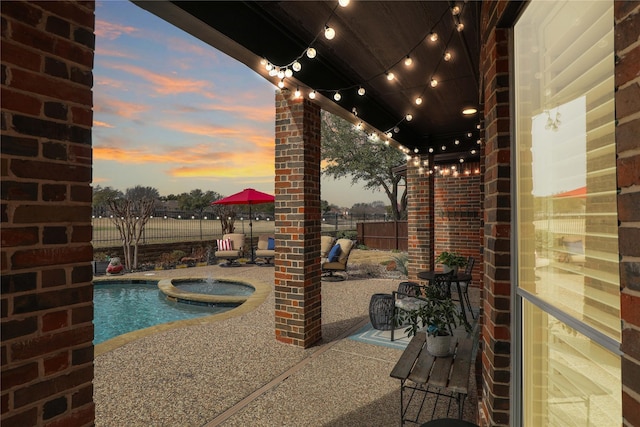 pool at dusk with a patio area, a fenced backyard, and a fenced in pool