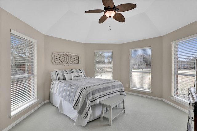 bedroom featuring light colored carpet, vaulted ceiling, baseboards, and ceiling fan