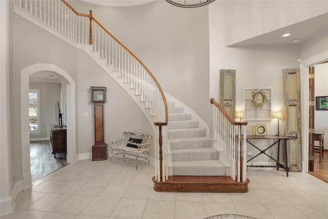 5224 N Meadow Ridge Cir, Mckinney, TX 75072 - staircase with a towering ceiling, arched walkways, tile patterned floors, and baseboards