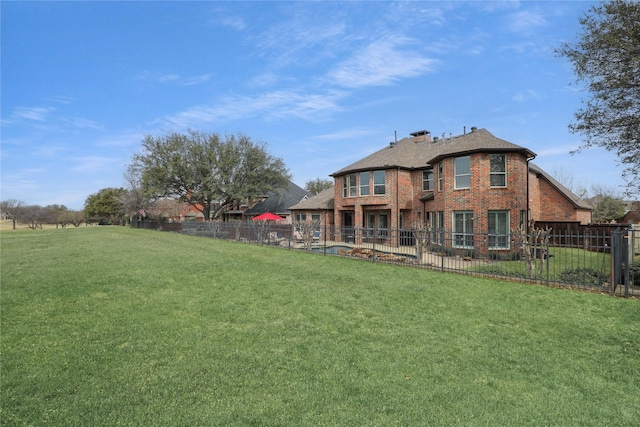 rear view of house featuring brick siding, a lawn, and fence