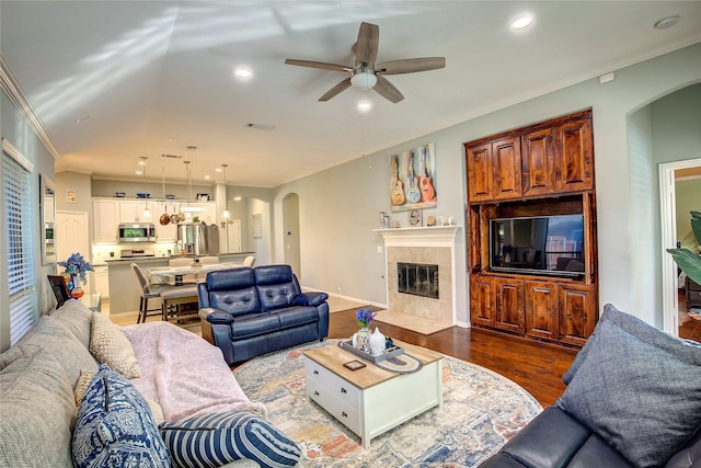 living room featuring recessed lighting, visible vents, ornamental molding, wood finished floors, and a tile fireplace