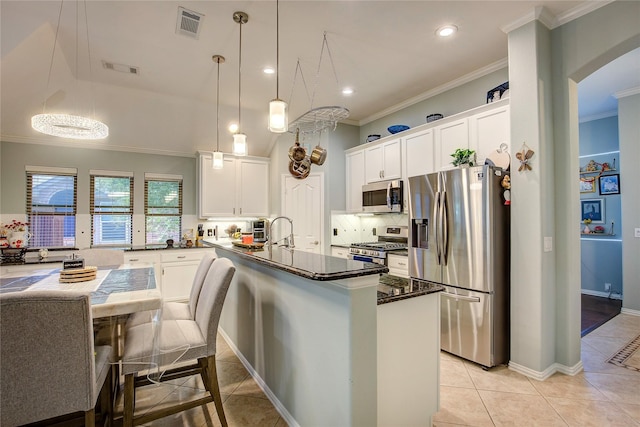 kitchen with a center island, decorative light fixtures, appliances with stainless steel finishes, ornamental molding, and white cabinets