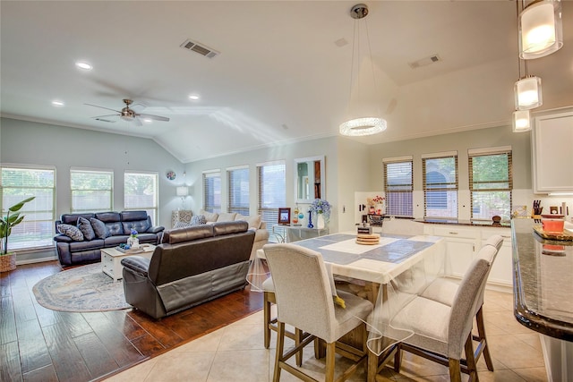 dining space with lofted ceiling, ornamental molding, light tile patterned floors, and visible vents