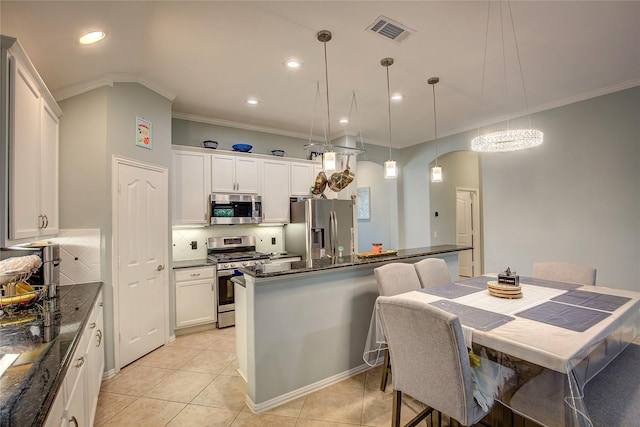 kitchen with decorative light fixtures, visible vents, appliances with stainless steel finishes, white cabinets, and a kitchen island